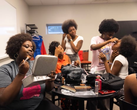 black women sit and stand while putting on makeup to get ready