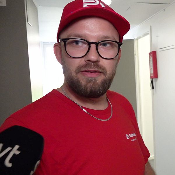 Studentkorridor i Umeå och en man i röd tröja i förgrunden.