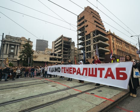 Students and protesters stand on a site in front of part-destroyed buildings holding a banner which reads: 'We won’t give up the General Staff building.’