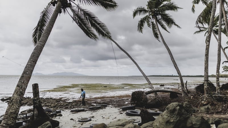 A man walks along a coast that is washed away by the rising sea level