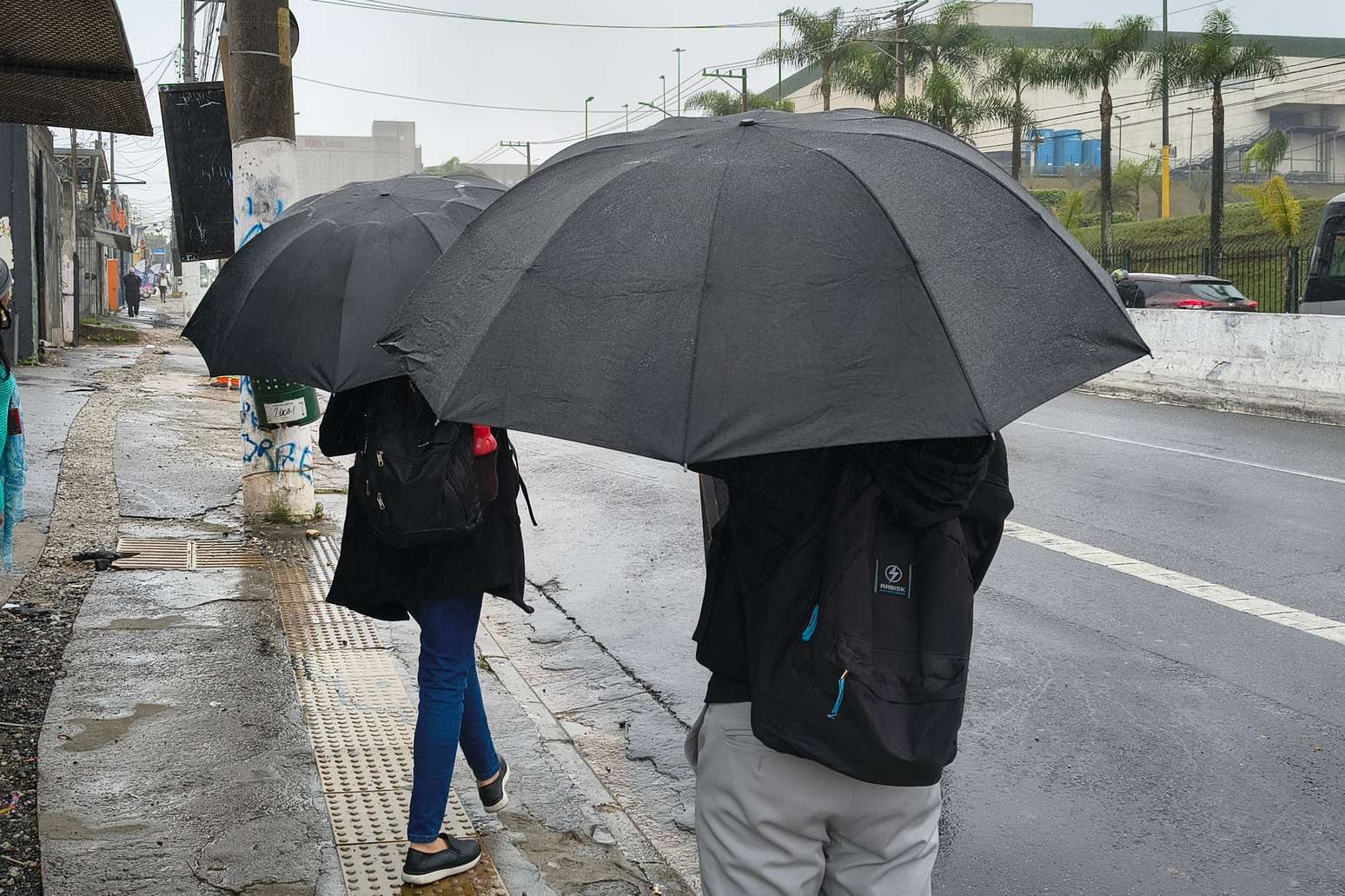 Pedestres se protegem da chuva na Avenida Interlagos, no Jardim Consórcio, zona sul de São Paulo, nesta sexta-feira, 2 de outubro de 2026